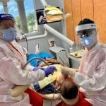 Staff with full PPE working on a patient 2 in dental chair Flagler Dental Clinic of Miami