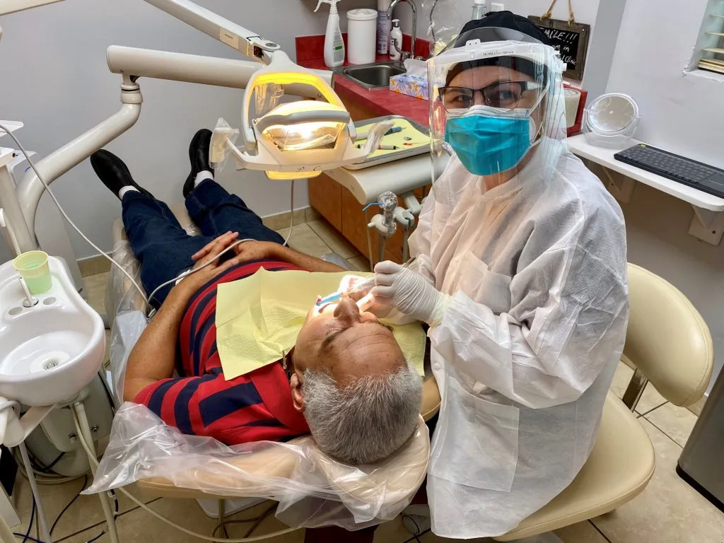 Staff with full PPE working on a patient in dental chair Flagler Dental Clinic of Miami