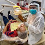 Staff with full PPE working on a patient in dental chair Flagler Dental Clinic of Miami